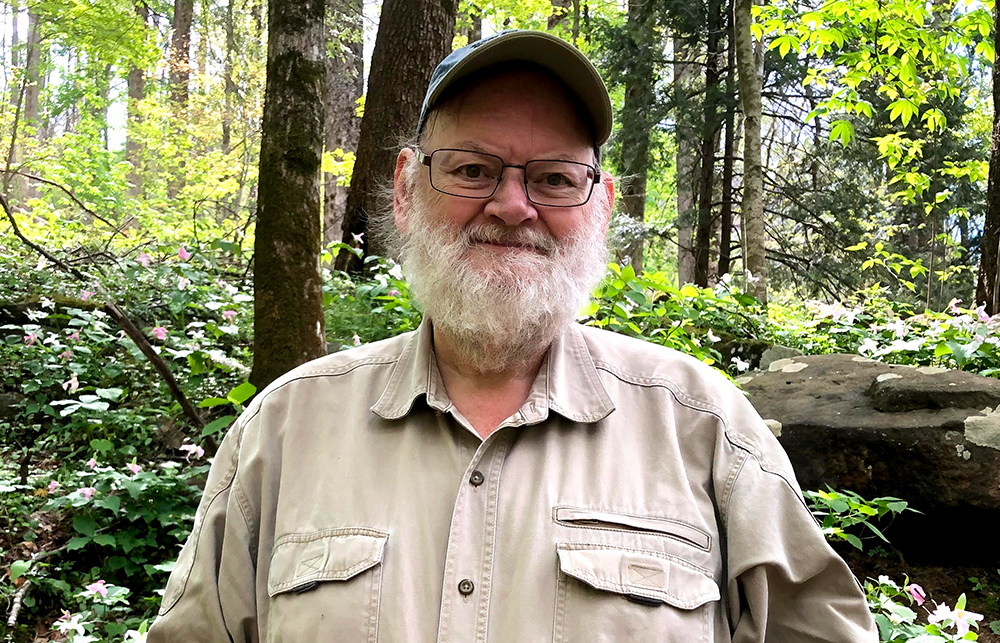 James Cheverud smiles in front of a forest background